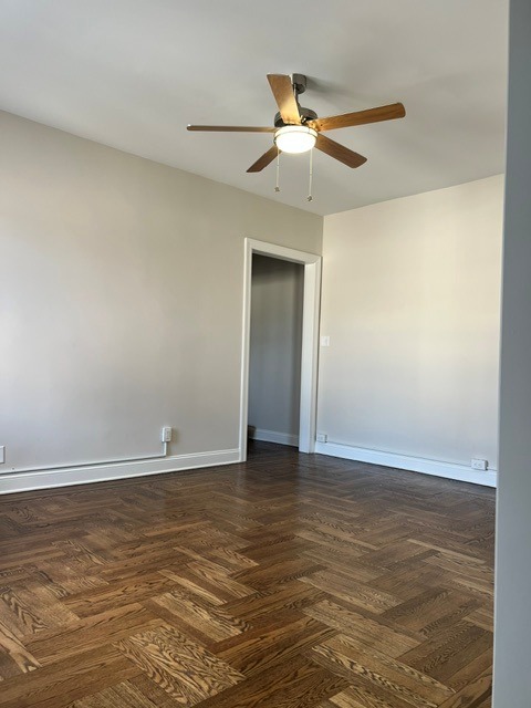 A room with a ceiling fan and wooden flooring.